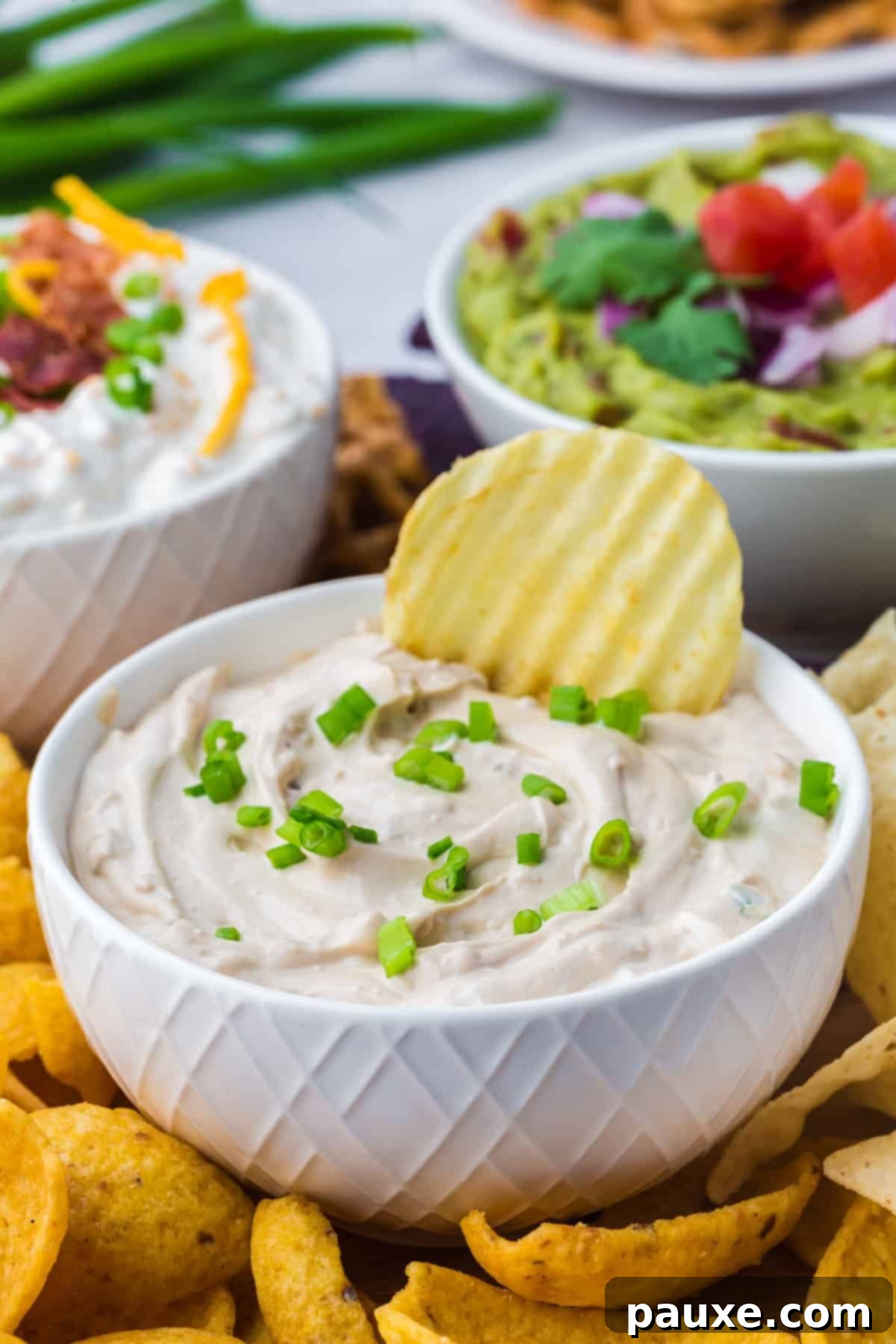 Quick & Creamy French Onion Dip 2 A chip being dipped into a bowl of french onion dip.