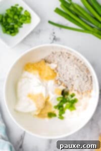 Quick & Creamy French Onion Dip 9 A white bowl filled with sour cream, onion mix, garlic, green onions, etc.