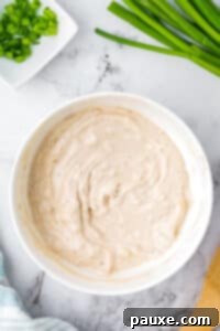 Quick & Creamy French Onion Dip 10 A bowl of onion dip, with green onions around the edges.