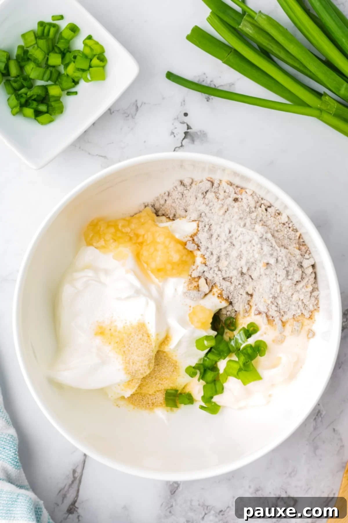 Quick & Creamy French Onion Dip 4 A white bowl filled with sour cream, onion mix, garlic, green onions, etc.