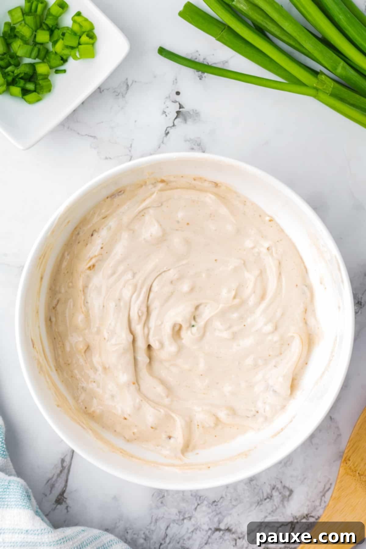 Quick & Creamy French Onion Dip 5 A bowl of onion dip, with green onions around the edges.