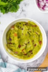 Perfectly Chunky Guacamole 10 A bowl of guacamole featuring chunks of tomato, mixed and ready for chilling.