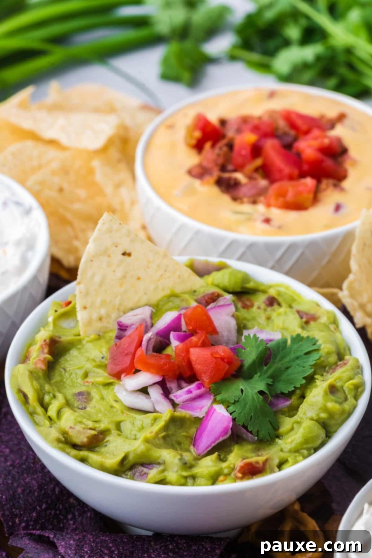 Perfectly Chunky Guacamole 7 A bowl of chunky avocado dip with a tortilla chip being dunked into it, showcasing the rich texture.