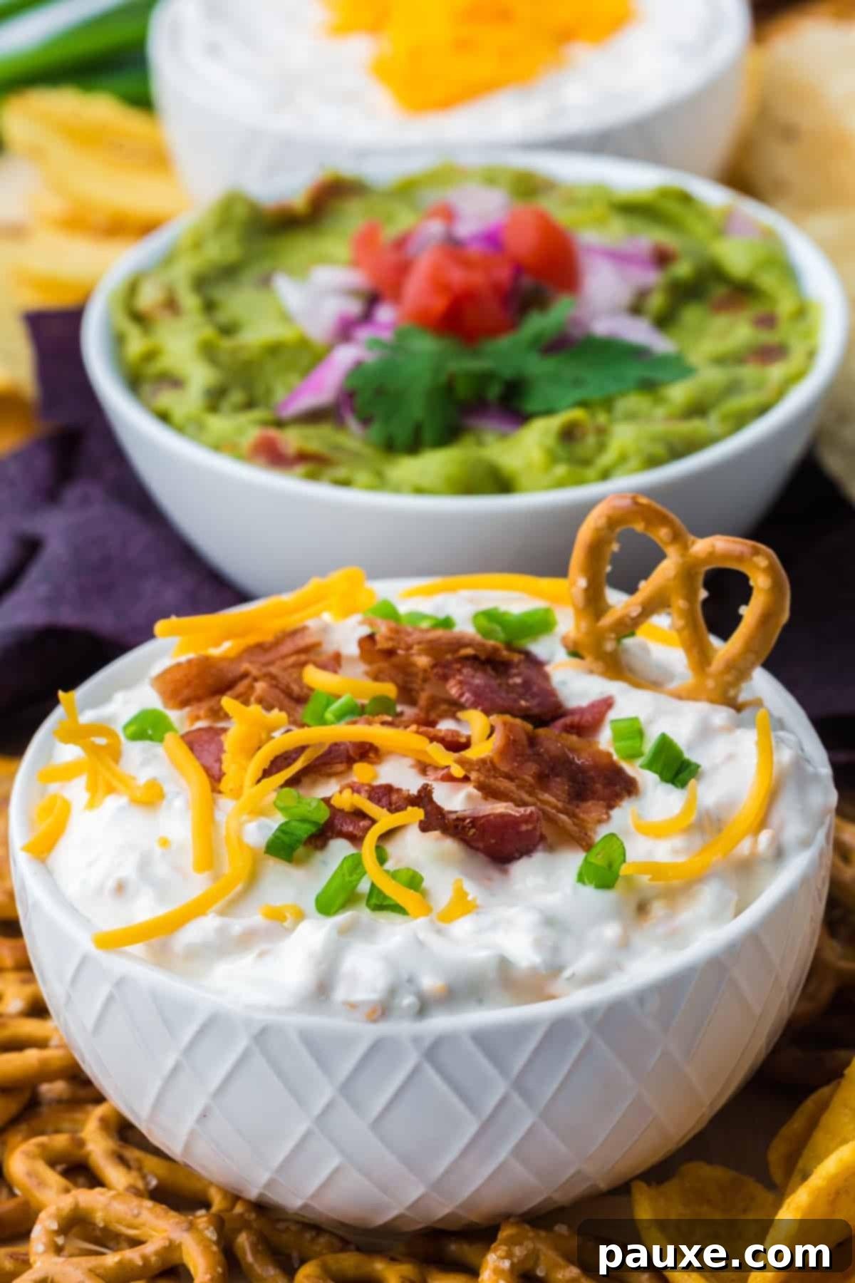 Deconstructed Baked Potato Dip 2 A bowl of creamy loaded baked potato dip with a crunchy pretzel stick dipped into it, ready to serve.