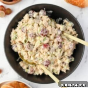 A black bowl filled with creamy chicken salad dotted with grapes.