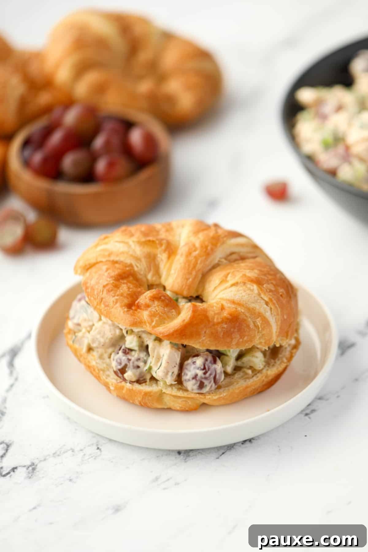 A golden, flaky croissant sliced in half and generously filled with creamy chicken salad.