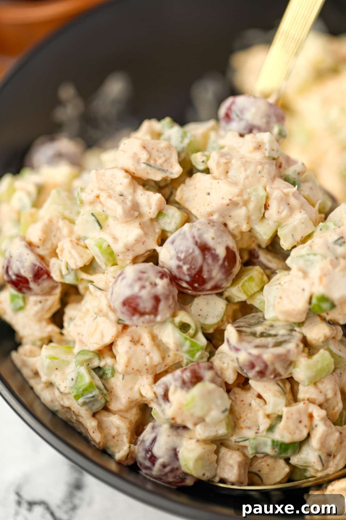 A close-up shot of creamy chicken salad, beautifully dotted with vibrant red grapes.