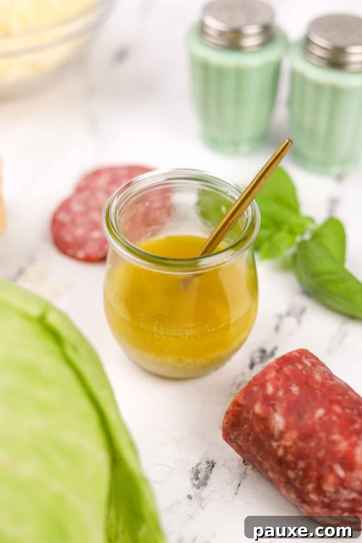 Leon's Signature Dressing 2 A small glass jar filled with bright, golden vinaigrette dressing, indicating a fresh and homemade quality.