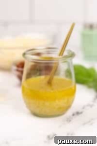 Leon's Signature Dressing 13 A small jar of homemade vinaigrette with a gold spoon inside, prepared for serving.