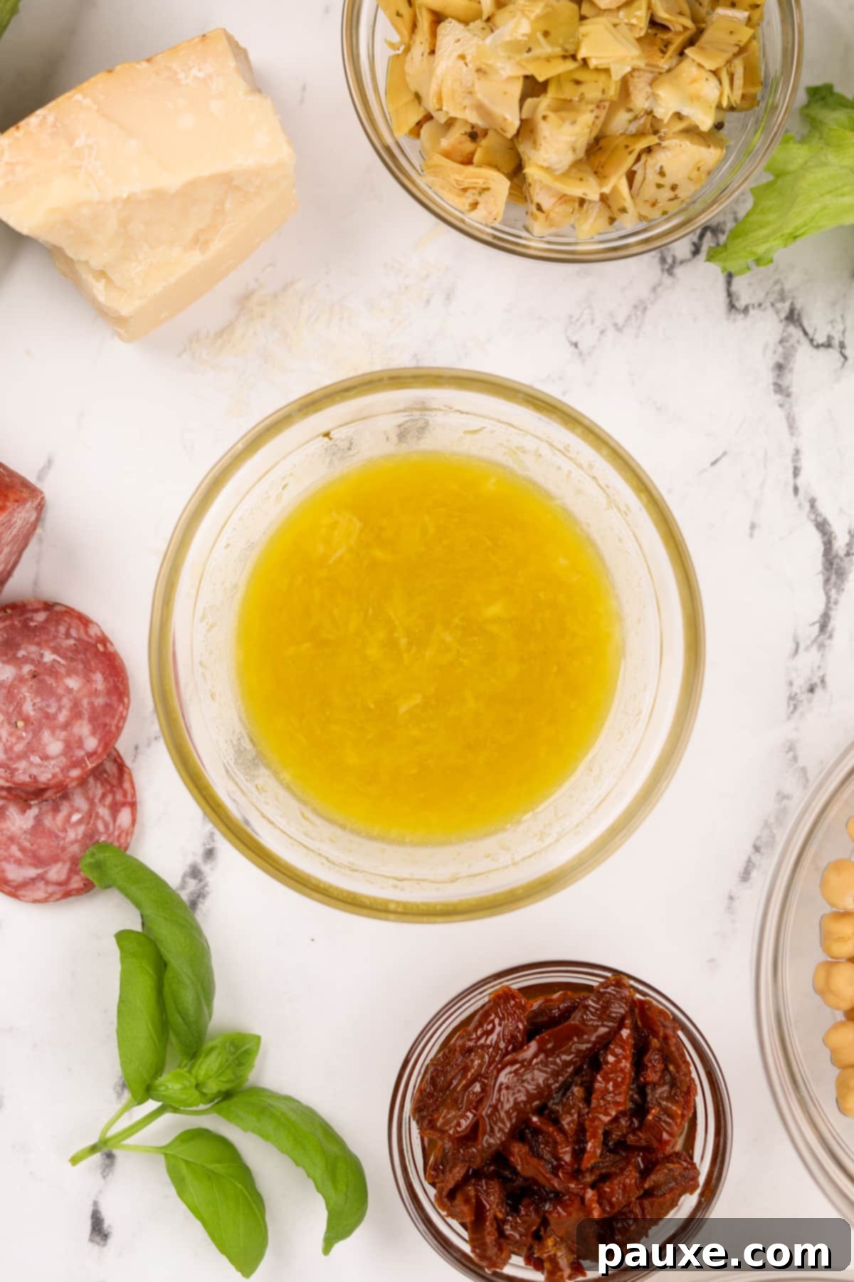 Leon's Signature Dressing 6 A vibrant bowl of freshly made vinaigrette, surrounded by colorful antipasto ingredients like olives, cheese, and cured meats, suggesting diverse serving possibilities.