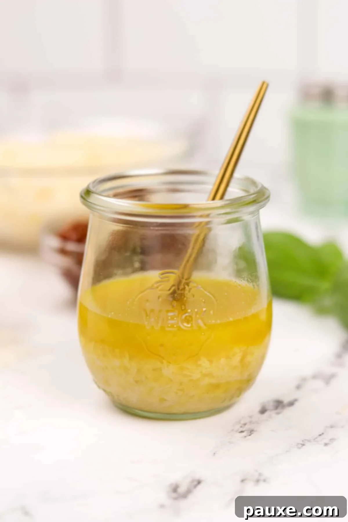 Leon's Signature Dressing 9 A small glass jar of homemade vinaigrette, with a small gold spoon resting inside, presented invitingly.