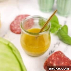 Leon's Signature Dressing 10 A small glass jar of homemade vinaigrette with a small spoon inside, visually appealing.