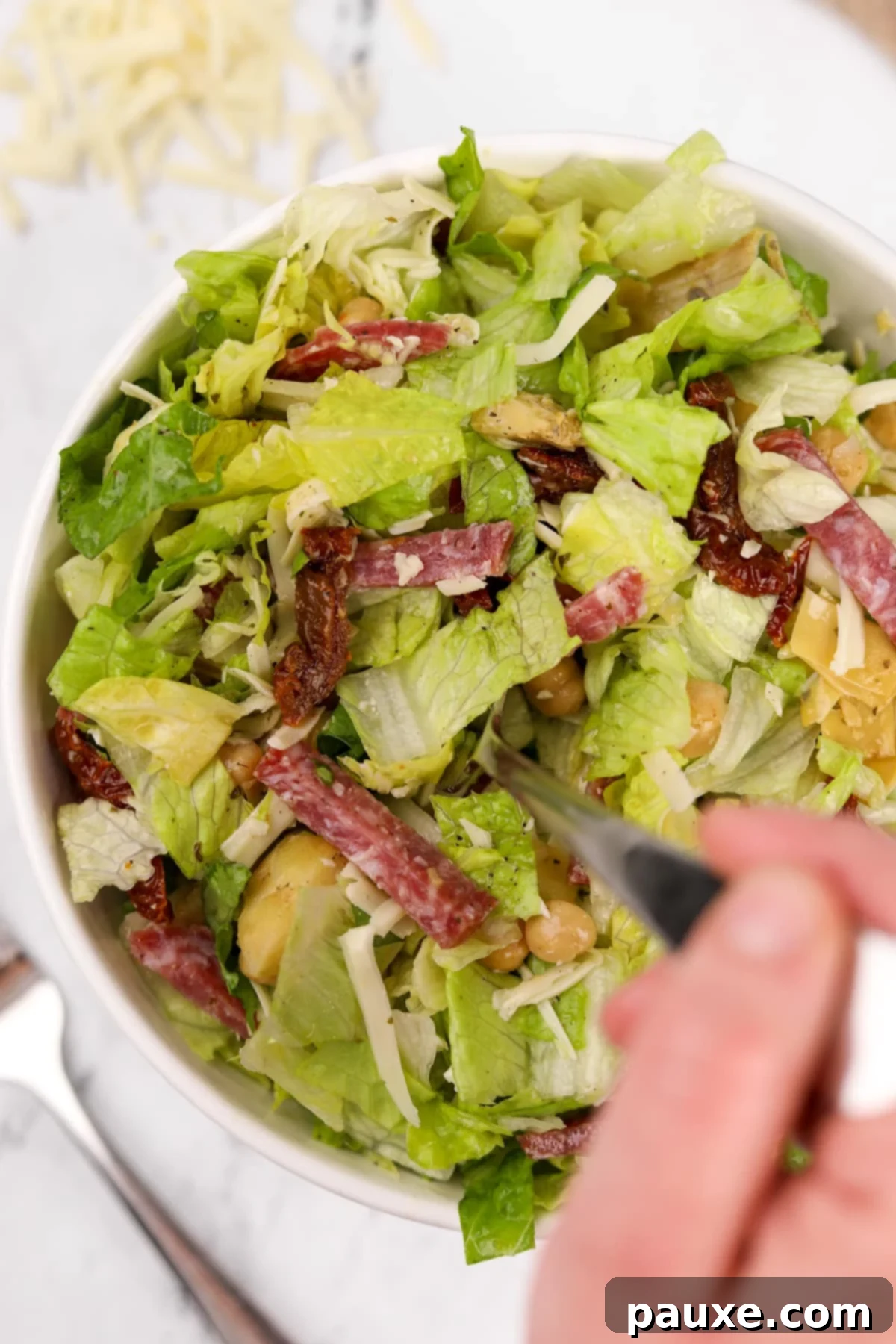 A close-up of a fork taking a bite of the La Scala Chopped Salad from a bowl, highlighting its fresh ingredients.