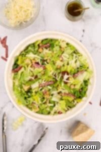 A bowl of chopped salad featuring chopped salami pieces.