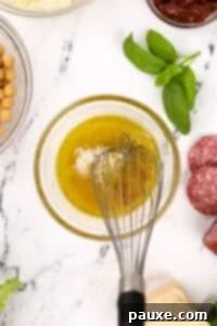 Whisking together a dressing that includes olive oil and parmesan cheese.