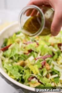 Pouring salad dressing over a chopped salad.