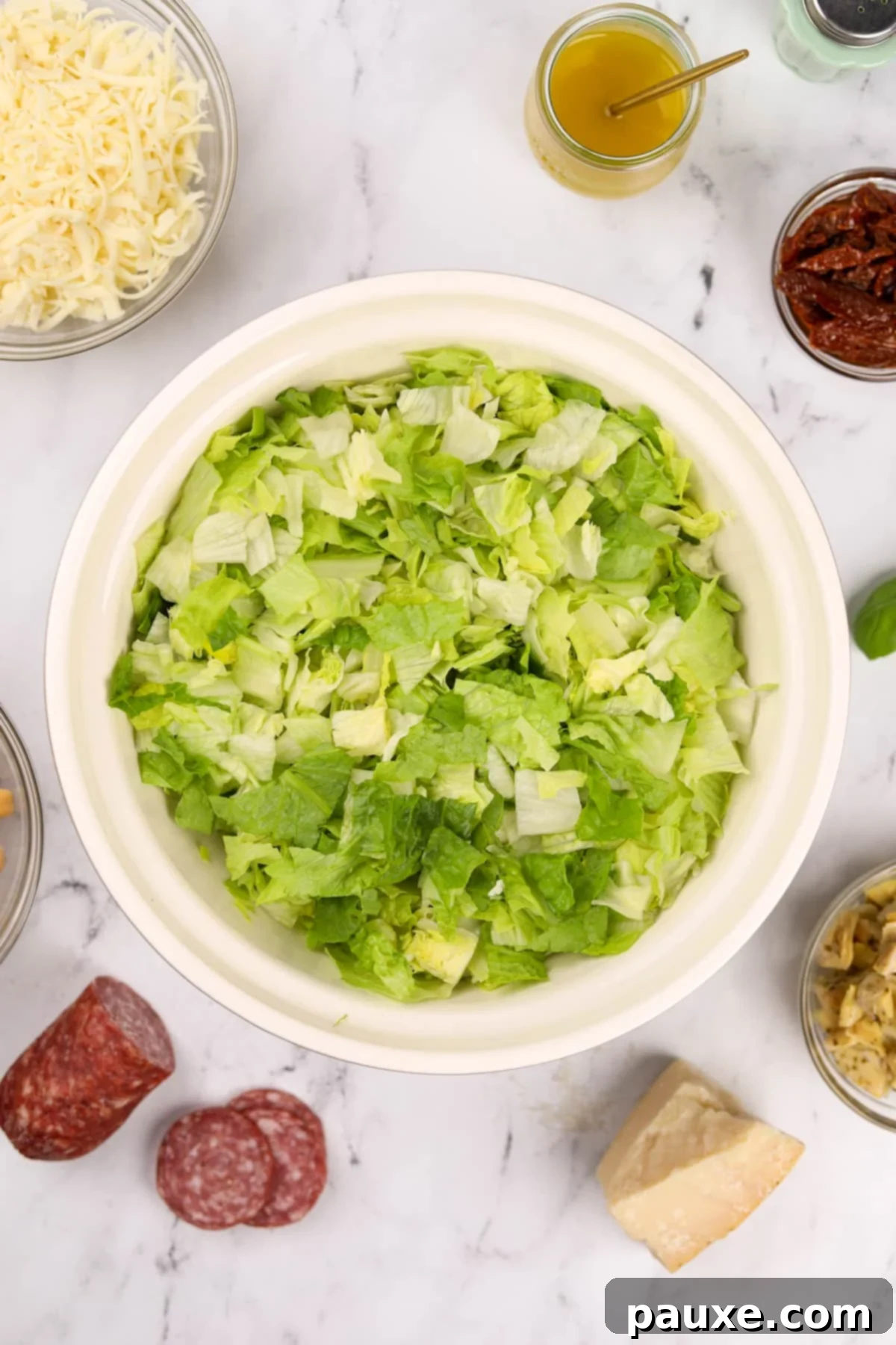 A large bowl filled with finely chopped romaine and iceberg lettuce, prepped for the salad.