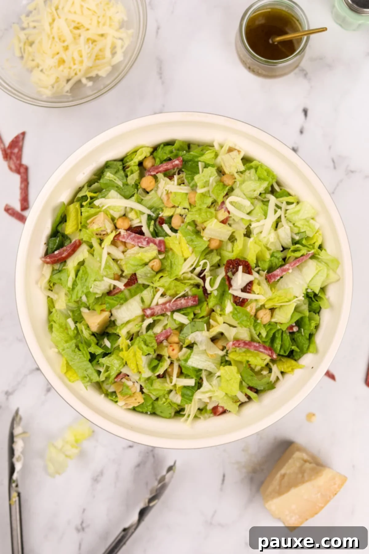 A vibrant bowl of chopped salad, showcasing the abundance of chopped salami pieces mixed throughout the greens.