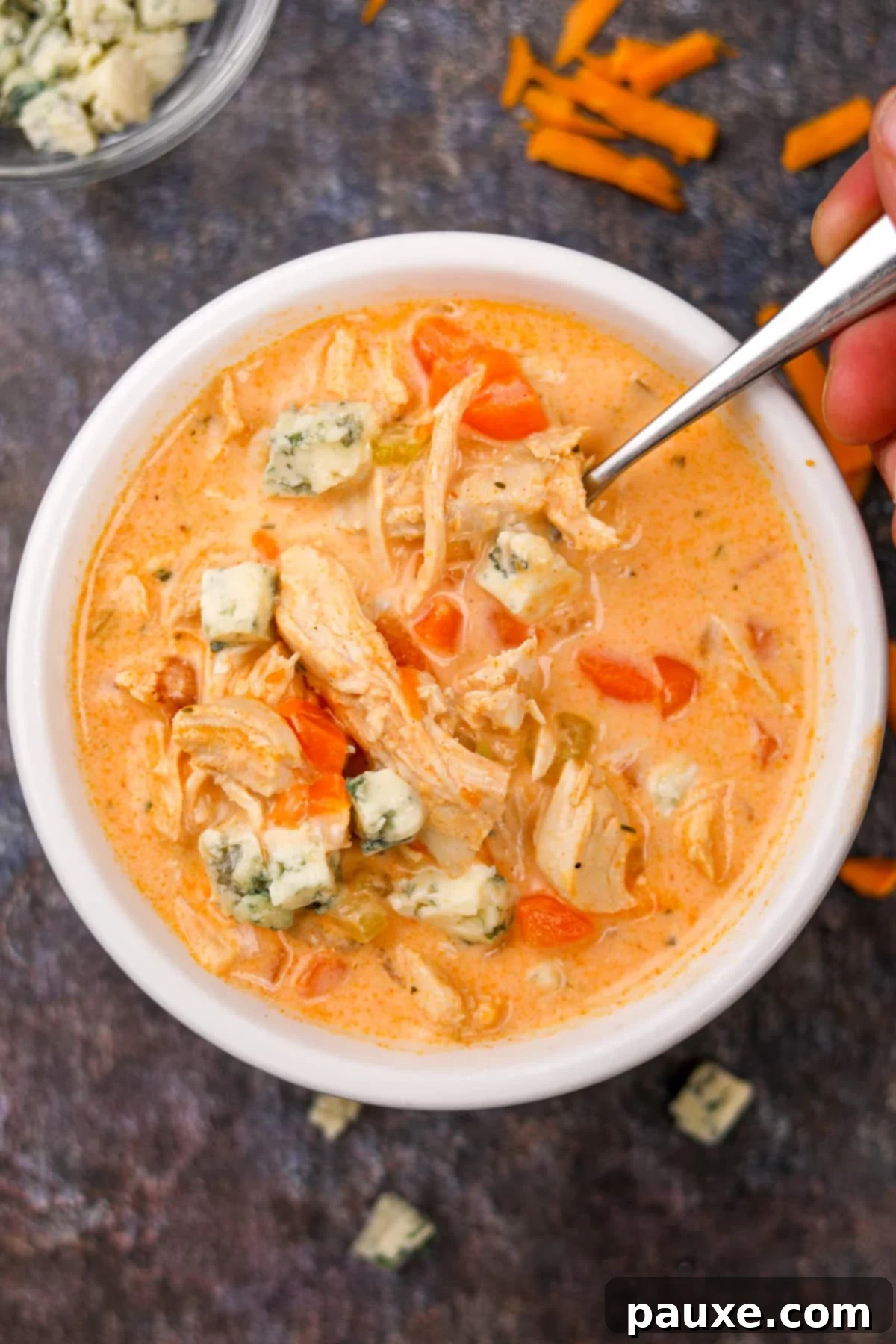 Spicy Buffalo Chicken Chowder 8 A hearty bowl of spicy chicken soup with a spoon resting in it, ready for a comforting meal.