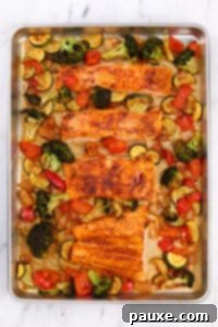 A sheet pan with roasted vegetables and salmon fillets.