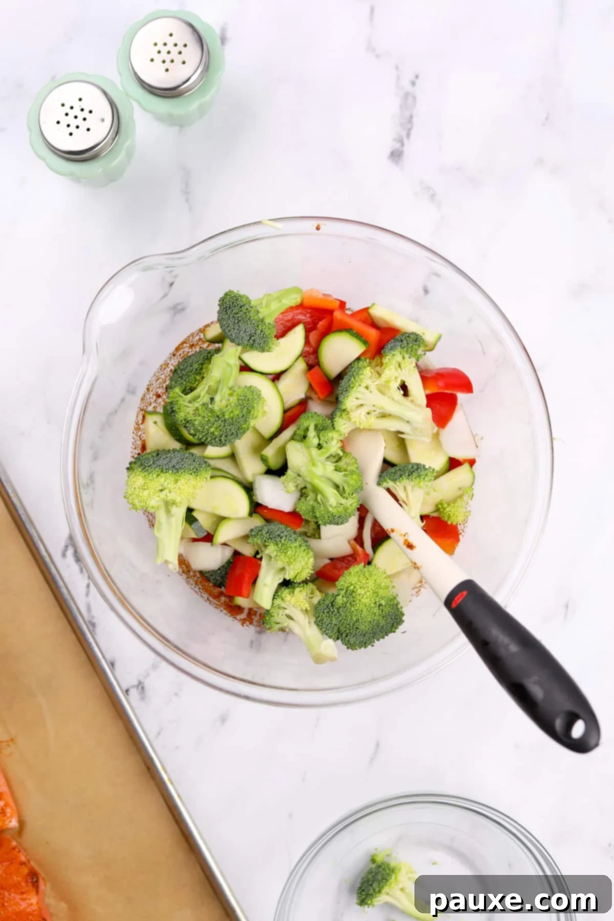 A bowl with various cut vegetables: broccoli, bell pepper, onion, and zucchini.
