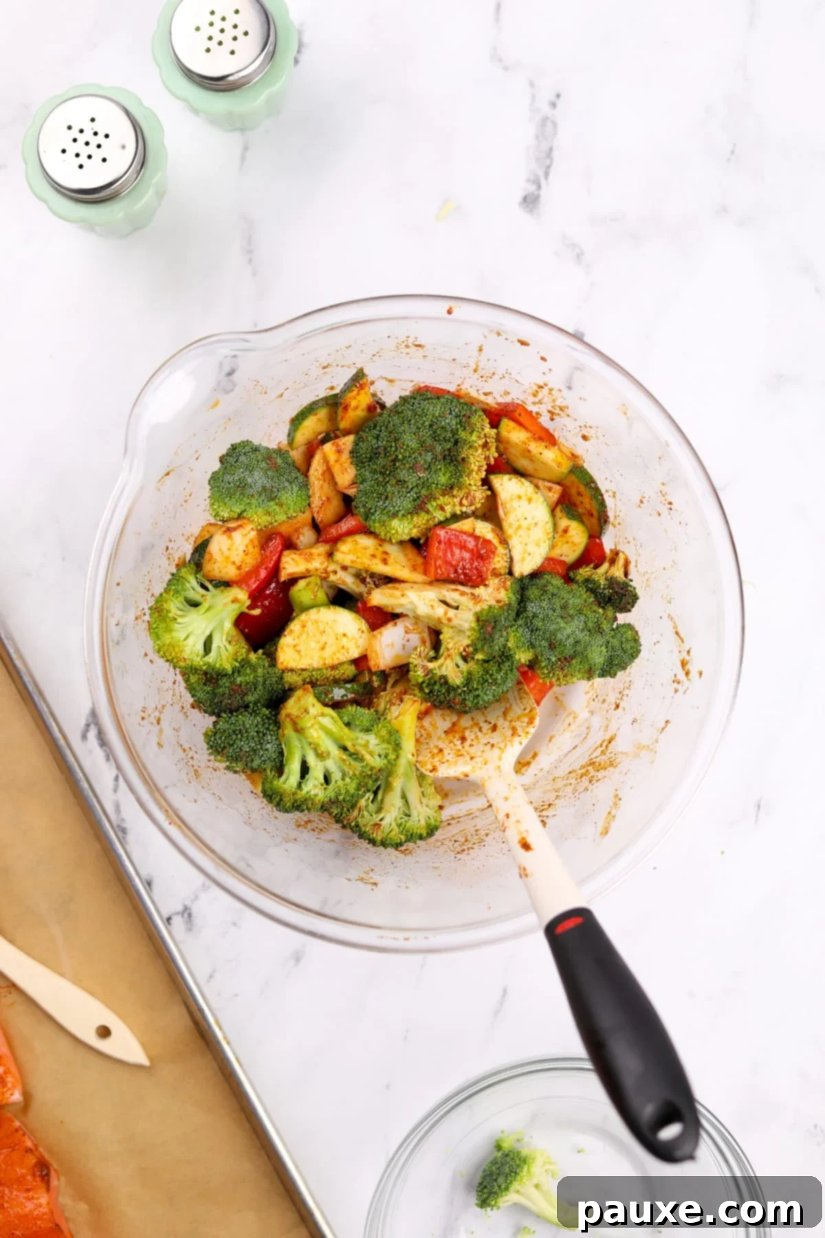 A large bowl with seasoned vegetables being stirred.