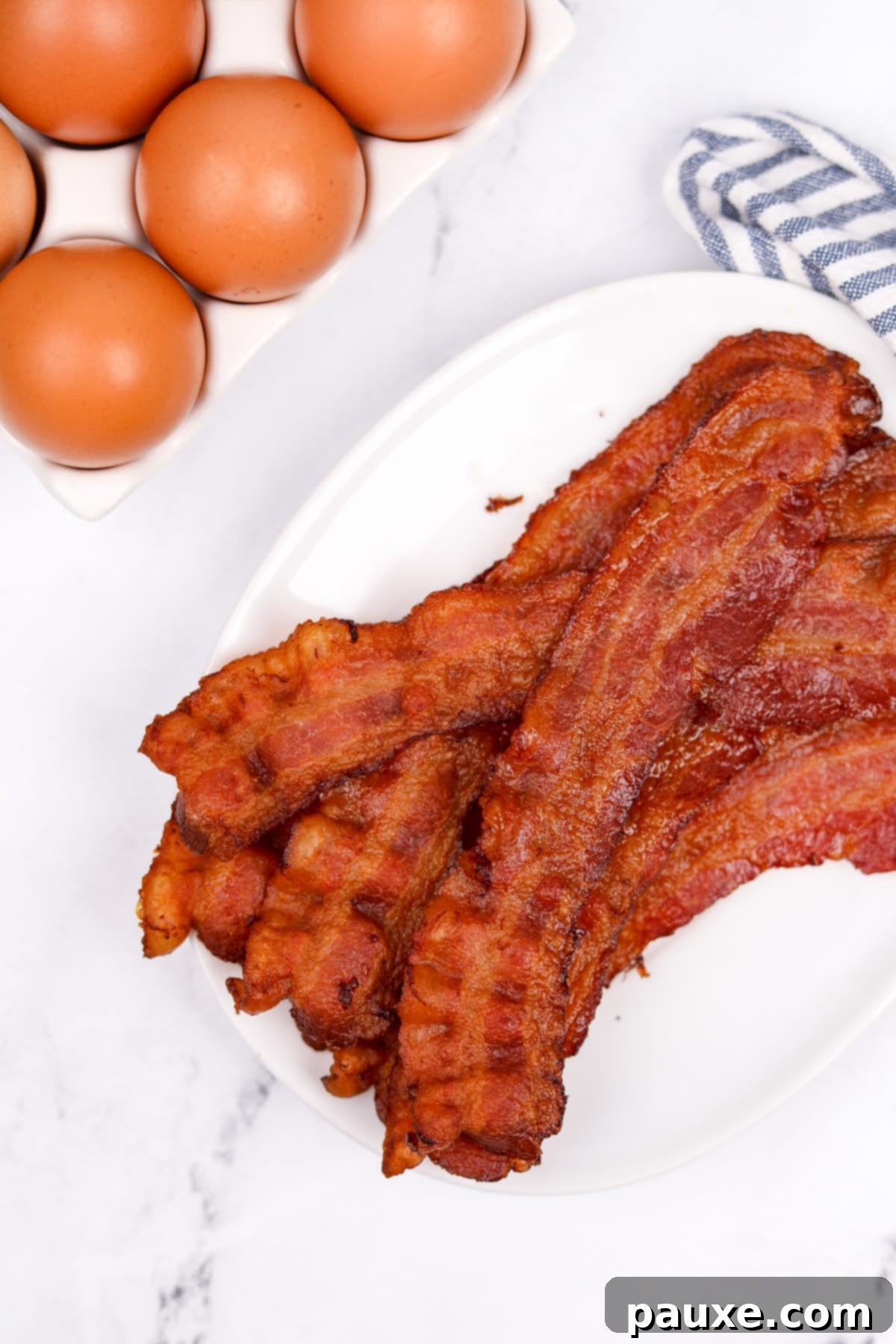 Perfectly Crispy Oven Bacon 8 Perfectly crispy, golden-brown bacon slices neatly arranged on a simple white plate, highlighting their appetizing texture.