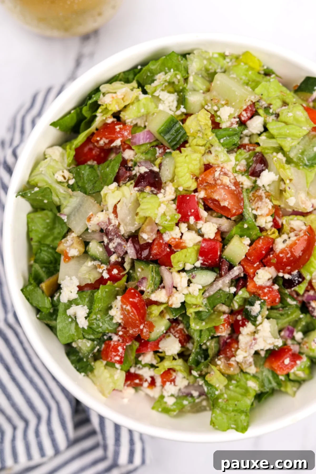 Vibrant Greek Chopped Salad 2 A vibrant bowl of fresh Greek chopped salad, featuring crisp romaine, juicy tomatoes, cucumber slices, red onion, black olives, and crumbled feta cheese, drizzled with a light vinaigrette.