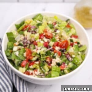 Vibrant Greek Chopped Salad 10 A white bowl filled with a leafy salad and Greek-inspired vegetables.