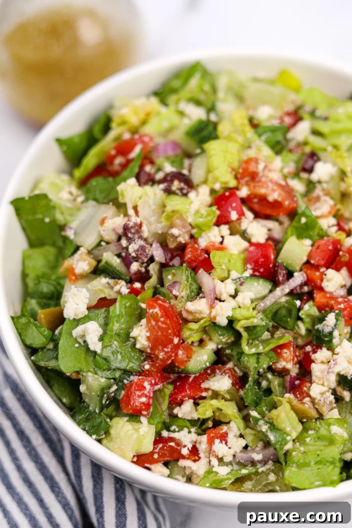Vibrant Greek Chopped Salad 9 A close-up view of a bowl of Greek chopped salad, highlighting the vibrant colors and textures of feta cheese, cherry tomatoes, cucumbers, and Kalamata olives mixed with romaine lettuce.