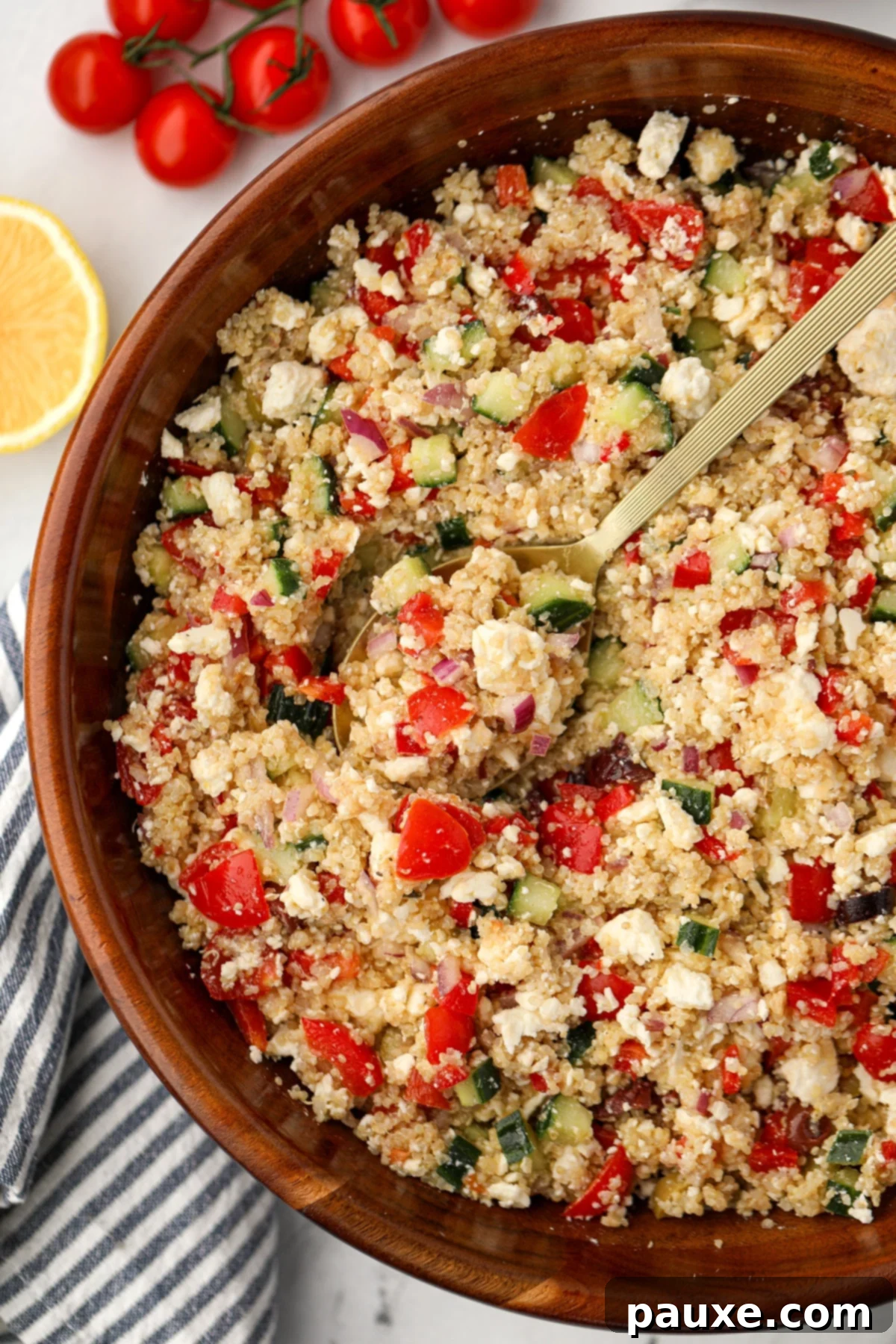Zesty Mediterranean Quinoa Salad 2 A large salad bowl overflowing with a vibrant Greek Quinoa Salad, showcasing chunks of red bell pepper, creamy feta, and refreshing cucumber.