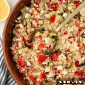 Zesty Mediterranean Quinoa Salad 8 A spoon scooping a portion of Greek quinoa salad from a large wooden bowl.
