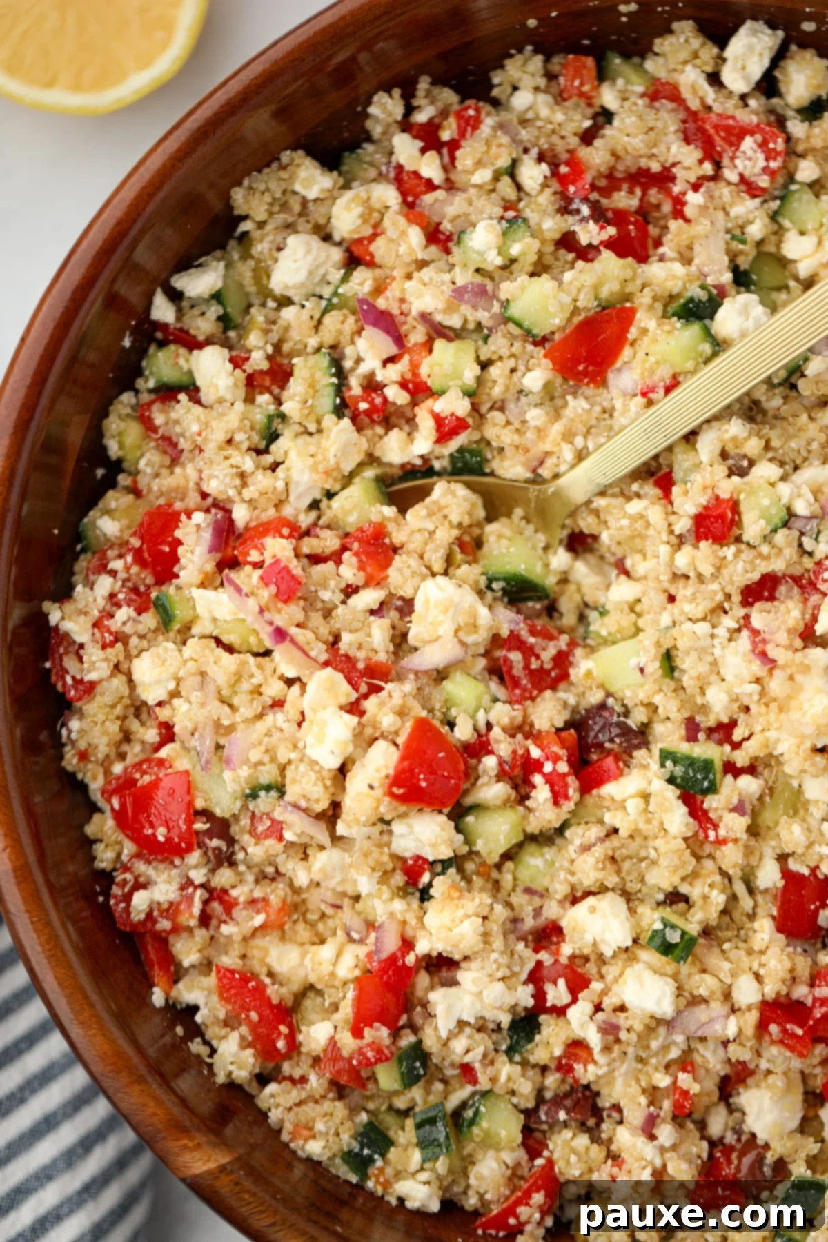 Zesty Mediterranean Quinoa Salad 7 A large serving spoon gracefully scoops a portion of the delicious Greek Quinoa Salad from a wide salad bowl, ready to be enjoyed.