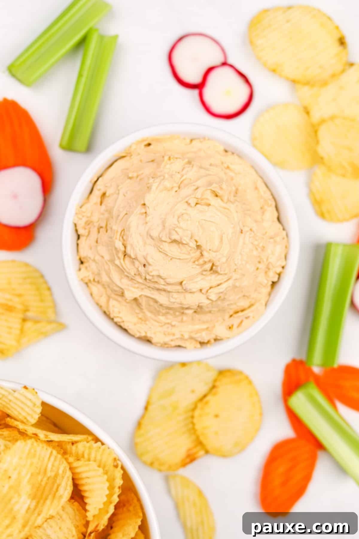 Golden State Creamy Dip 2 A beautifully presented bowl filled with classic California Dip (French Onion Dip), generously garnished and surrounded by a vibrant assortment of fresh, crisp vegetables and crispy potato chips, all ready for dipping.