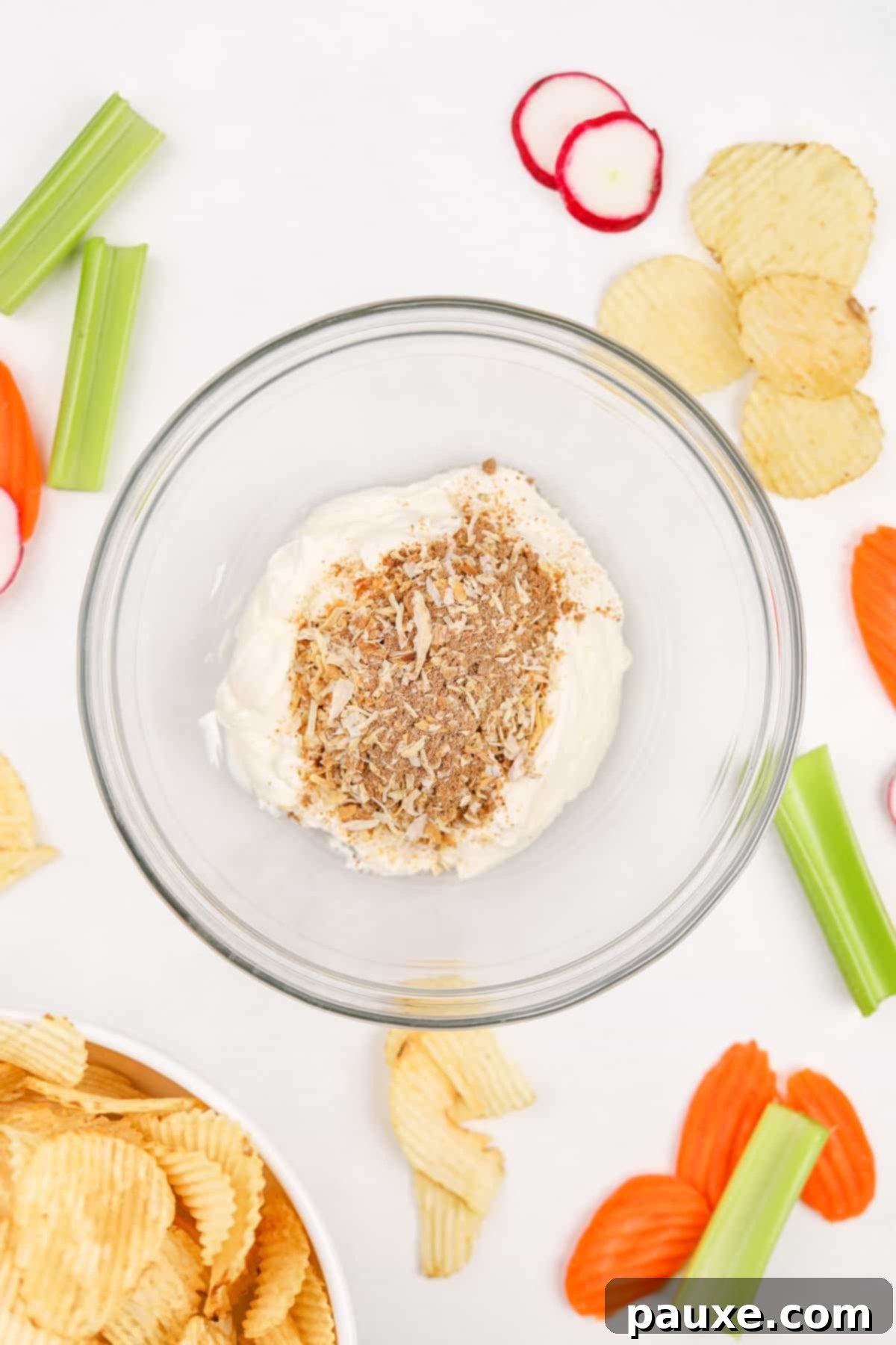 Golden State Creamy Dip 4 A medium-sized mixing bowl containing creamy sour cream and a packet of dry onion soup mix, captured just before they are combined, showing the distinct textures.