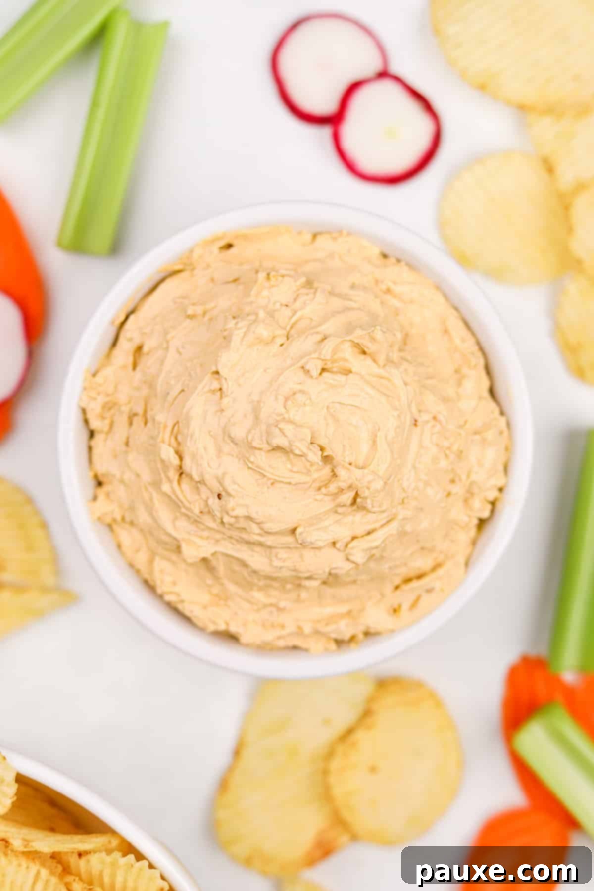 Golden State Creamy Dip 6 A beautifully presented bowl of creamy California Dip, ready for a gathering, surrounded by an array of fresh, colorful vegetables and crunchy potato chips, perfect for a party spread.