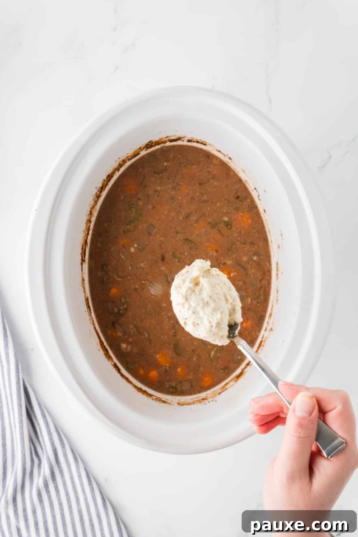 Comforting Slow Cooker Beef Stew and Dumplings 11 Dropping spoonfuls of soft dumpling dough directly into the hot beef stew within the slow cooker.