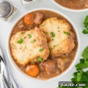 Comforting Slow Cooker Beef Stew and Dumplings 17 A white bowl filled with comforting beef stew, crowned with two homemade dumplings and a touch of green garnish.