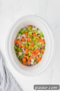 Comforting Slow Cooker Beef Stew and Dumplings 19 A slow cooker with beef cubes, celery, carrots, and onions layered inside.