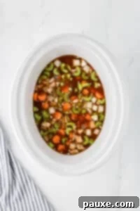 Comforting Slow Cooker Beef Stew and Dumplings 21 A slow cooker with vegetables and beef broth.