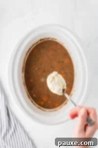 Comforting Slow Cooker Beef Stew and Dumplings 23 Dropping dumpling dough into a slow cooker filled with beef stew.