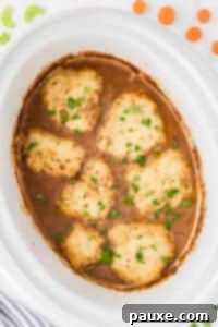 Comforting Slow Cooker Beef Stew and Dumplings 24 A white slow cooker insert filled with beef stew topped with homemade dumplings.