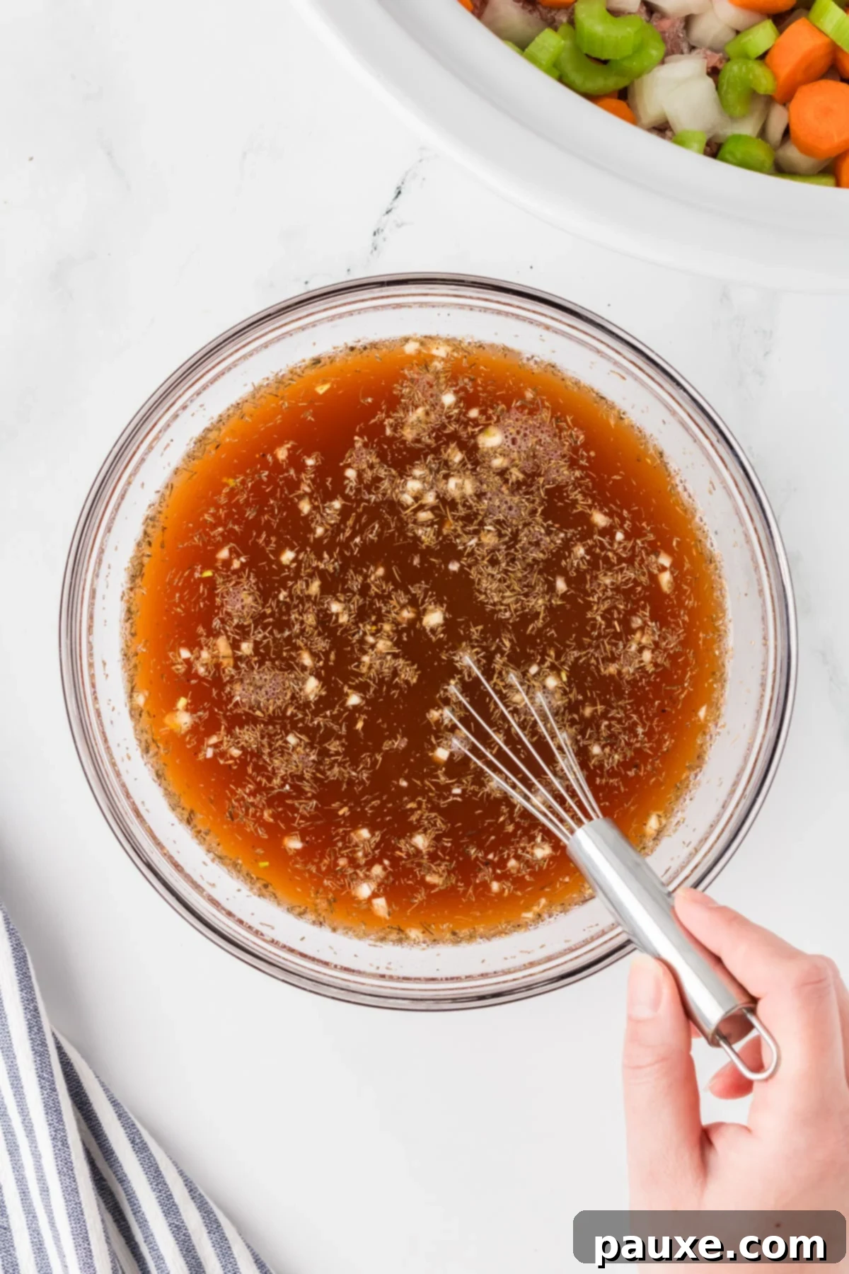 Comforting Slow Cooker Beef Stew and Dumplings 6 A medium bowl containing beef broth, tomato paste, Worcestershire sauce, garlic, and dried thyme, being whisked together.