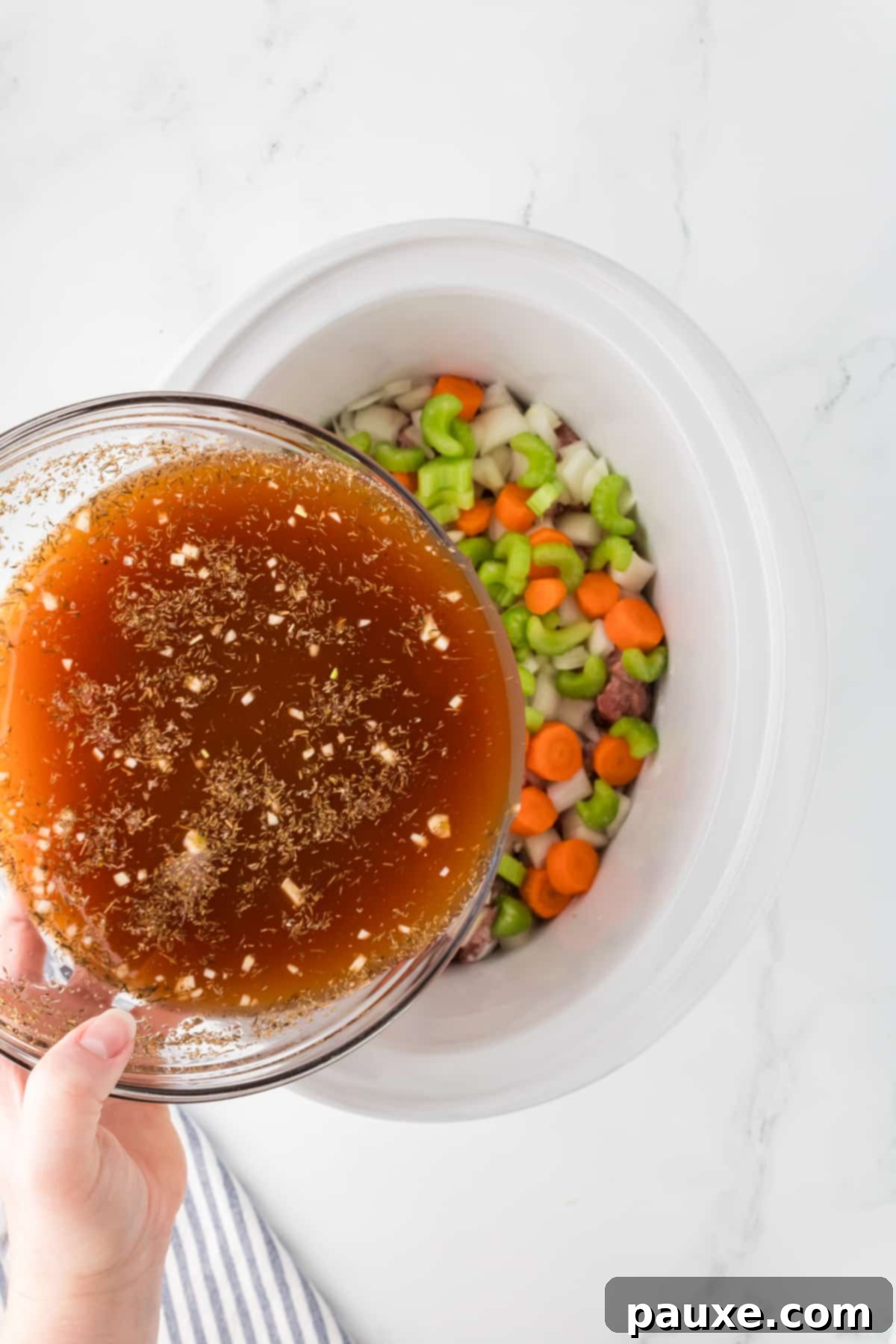 Comforting Slow Cooker Beef Stew and Dumplings 7 Pouring the whisked beef broth mixture over the beef and vegetables in the slow cooker.