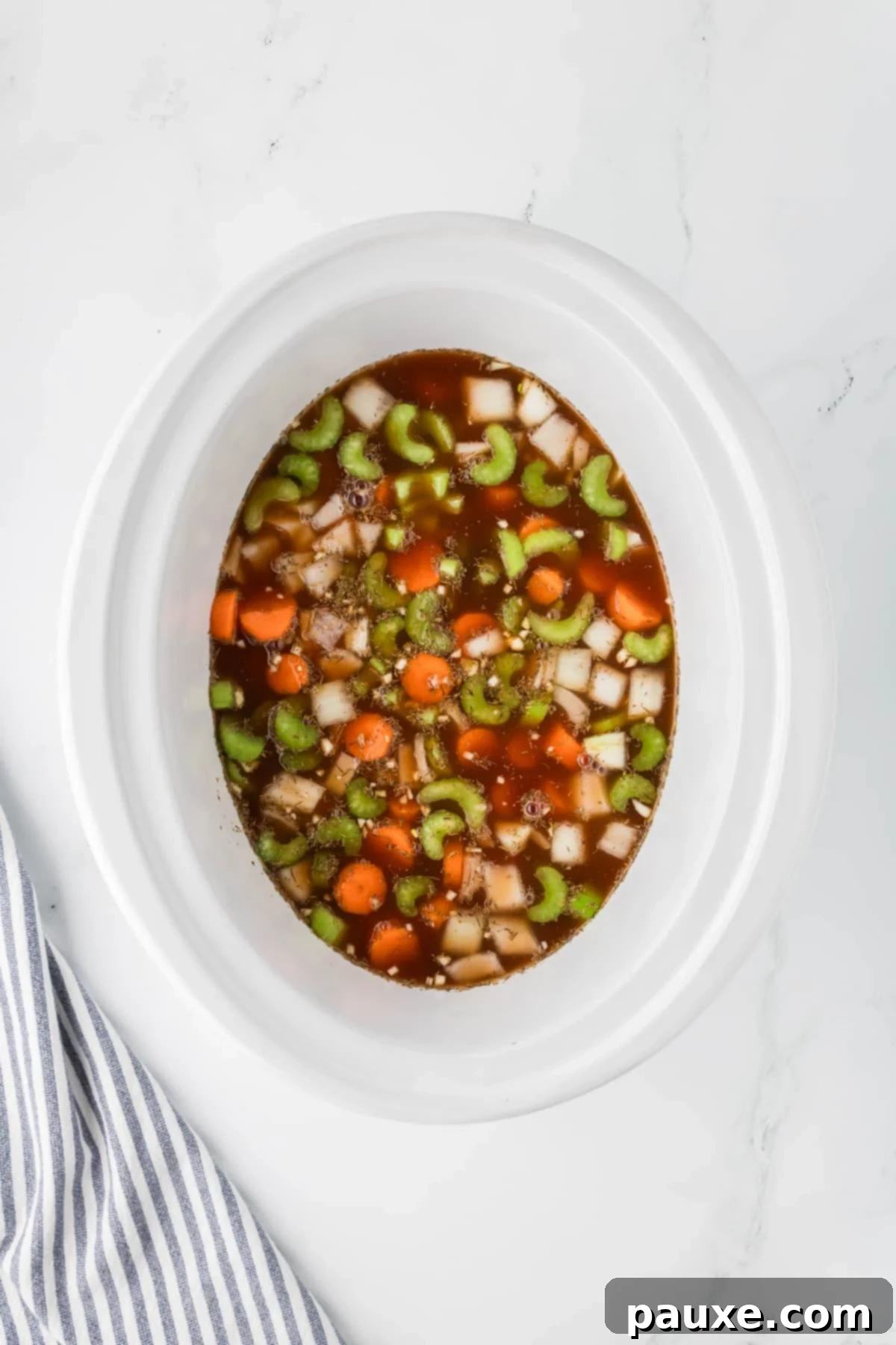 Comforting Slow Cooker Beef Stew and Dumplings 8 A slow cooker filled with beef and vegetables simmering in broth, covered and cooking on low heat.