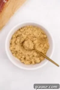 Crispy Caramelized Bacon 15 A small bowl of brown sugar being mixed with a small gold spoon.