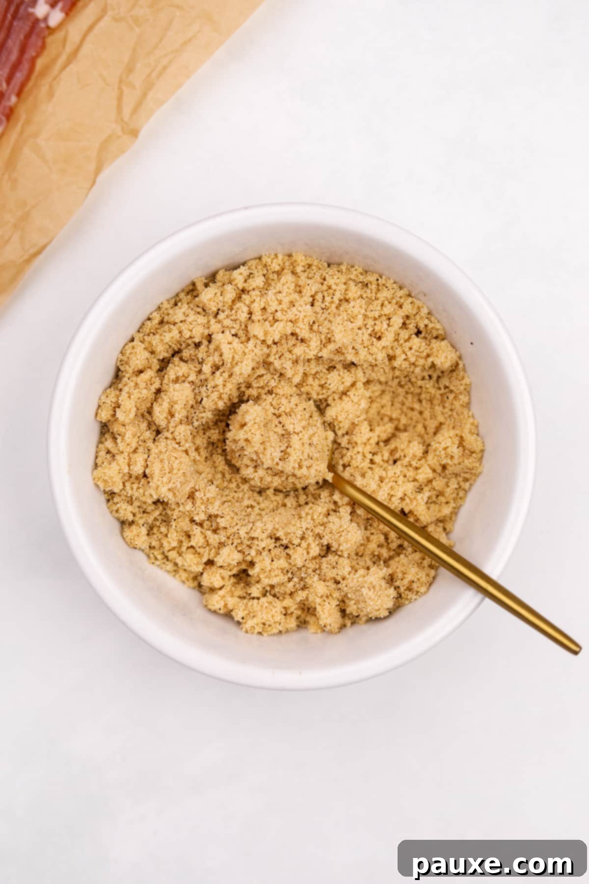 Crispy Caramelized Bacon 5 A small bowl of brown sugar being mixed with a small gold spoon.