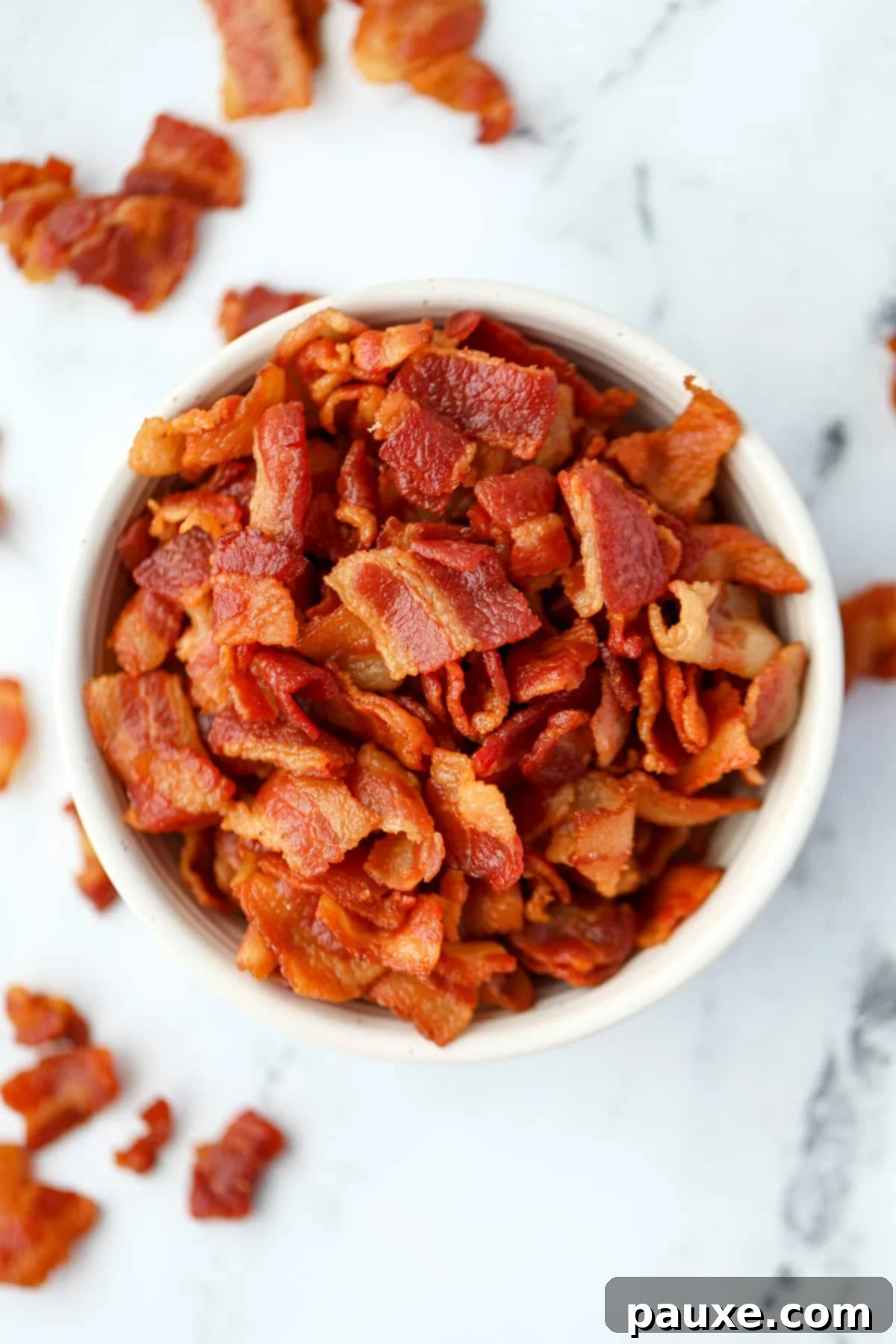 Crafting Crispy Homemade Bacon Bits 2 A pristine white ceramic bowl overflowing with golden-brown, perfectly cooked homemade bacon bits, ready to enhance any dish.