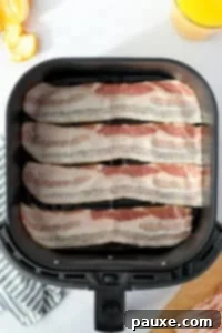 Crispy Air Fryer Bacon 11 Uncooked slices of bacon in an air fryer basket.