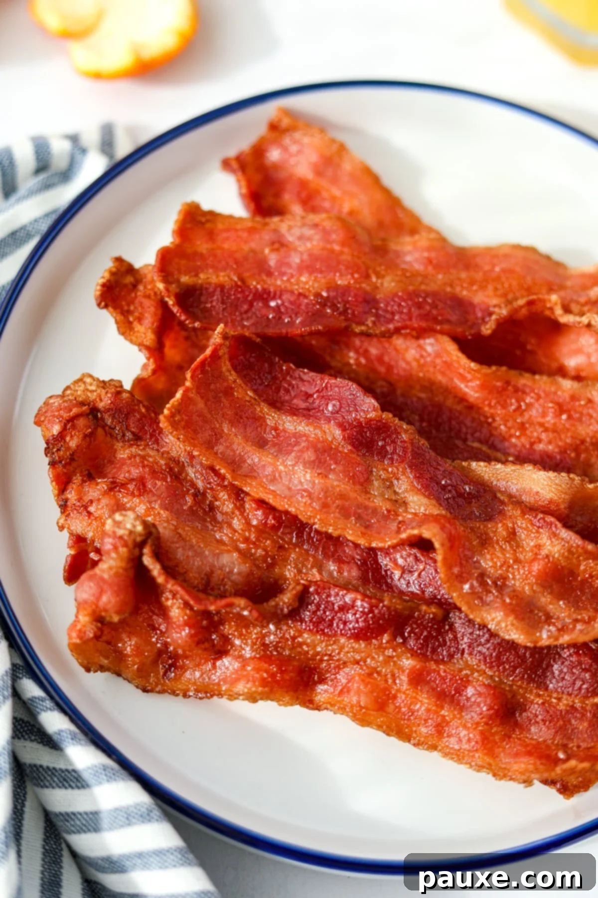 Crispy Air Fryer Bacon 8 A large pile of freshly cooked, crispy air fryer bacon on a white plate, ready to be served.